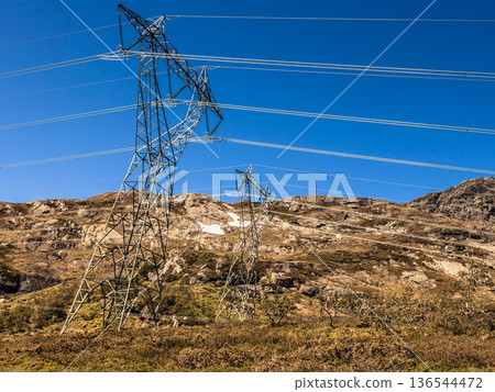 Power line voltage tower in mountains against blue sky Power line voltage tower in mountains against blue sky 136544472