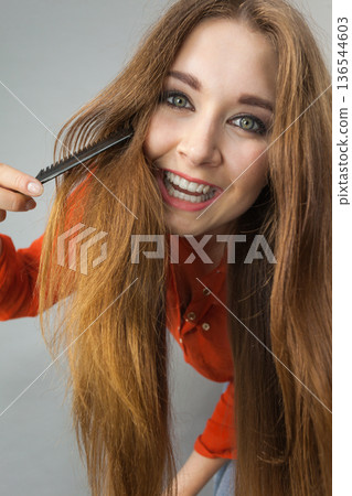 Woman combing her brown hair Woman combing her brown hair 136544603