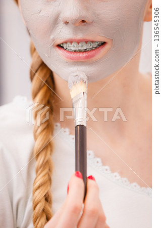 Woman applying with brush clay mud mask to her face 136545306