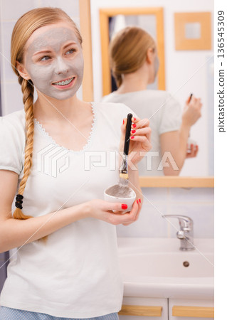 Happy young woman having mud mask on face Happy young woman having mud mask on face 136545309