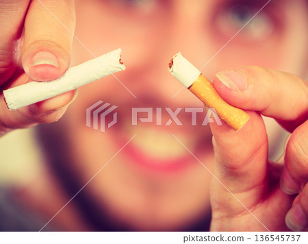 Smilling man is breaking a cigarette 136545737