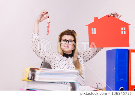 Happy business woman in office holding house Happy business woman in office holding house 136545755