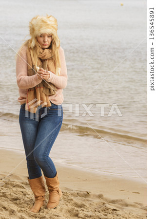 Woman in stylish outfit feeling cold by the sea Woman in stylish outfit feeling cold by the sea 136545891