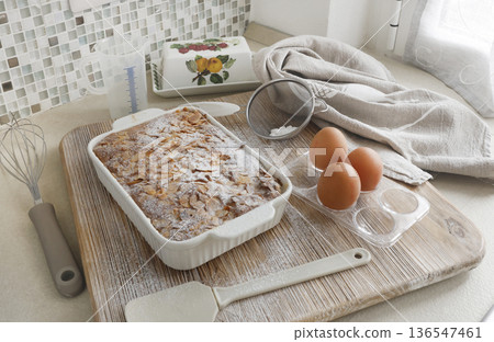 Sponge cake with petals, almond flakes, and powdered sugar. Dessert and home celebration. Cooking and hobbies. 136547461