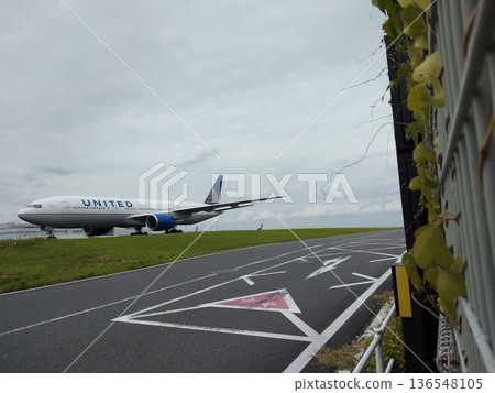 A United Airlines large passenger plane running on the runway A travel scene seen through the airport fence 136548105