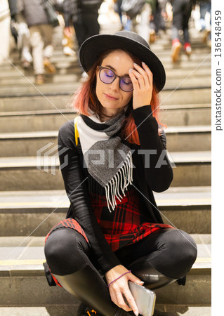 Young woman sitting on stairs experiencing urban stress Young woman sitting on stairs experiencing urban stress 136548459