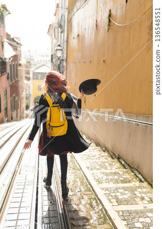 Woman with red hair walking down hilly street 136548551