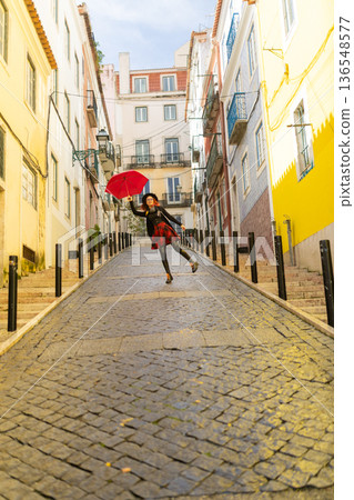 Woman with umbrella flying up a lisbon street Woman with umbrella flying up a lisbon street 136548577