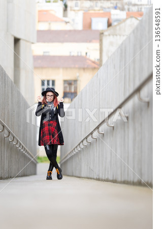 Stylish young woman standing on modern city walkway Stylish young woman standing on modern city walkway 136548591