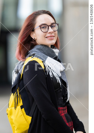 Millennial woman smiling wearing glasses and yellow backpack Millennial woman smiling wearing glasses and yellow backpack 136548606