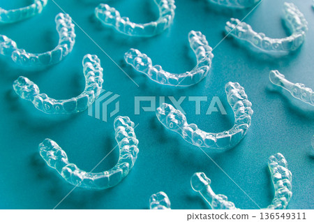 Clear orthodontic aligners arranged on a blue surface, showcasing their transparent design and dental structure for teeth straightening treatment 136549311