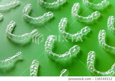 Dental background: many clear braces and aligners lie textured on a colored background. Dental technology Dental background: many clear braces and aligners lie textured on a colored background. Dental technology 136549312