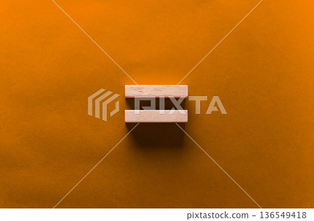 Two wooden blocks arranged horizontally on a vibrant orange background, showcasing a minimalist design with a focus on geometric shapes and color contrast 136549418