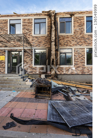 Charred vertical strip on brick wall marks fire path; broken window, scorched cabinet, and tangled wires lie amid debris in damaged urban setting. 136549999