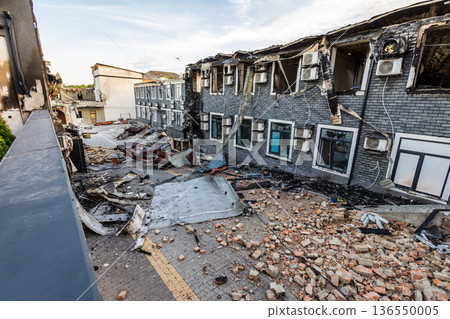 Bila Tserkva, Kyiv region, Ukraine 09.06.2025: Charred multi story building with broken windows, scattered debris, and intact air conditioners scene of localized fire damage amid urban surroundings. 136550005