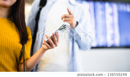 Men and women checking their smartphones at the airport. Photo courtesy of Kansai International Airport (KIX). 136550249