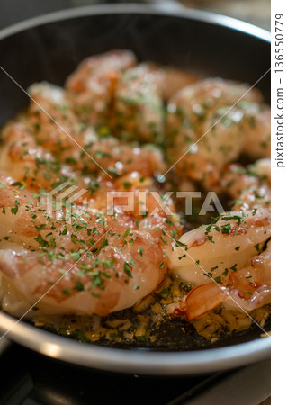 Shrimp saut ing in olive oil with garlic and parsley in a frying pan on the stove fresh, homemade seafood meal preparation Shrimp saut ing in olive oil with garlic and parsley in a frying pan on the stove fresh, homemade seafood meal preparation 136550779