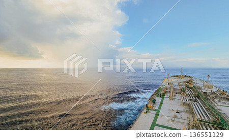 View from oil tanker deck sailing through vast ocean with dramatic clouds, contrasting sunlight, turbulent water near hull and isolated maritime scene View from oil tanker deck sailing through vast ocean with dramatic clouds, contrasting sunlight, turbulent water near hull and isolated maritime scene 136551129