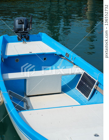 Blue motorboat equipped with a small solar panel and outboard engine floating on calm water,sustainable boating concept and clean renewable energy use Blue motorboat equipped with a small solar panel and outboard engine floating on calm water,sustainable boating concept and clean renewable energy use 136552732
