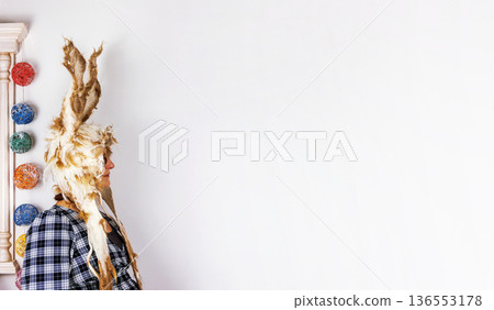 Woman wearing felted wool bunny hat with long ears standing against a white wall with copy space Woman wearing felted wool bunny hat with long ears standing against a white wall with copy space 136553178