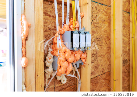 Electrical work in house with fire proof foam insulation covering wires switches on wooden wall Electrical work in house with fire proof foam insulation covering wires switches on wooden wall 136553819