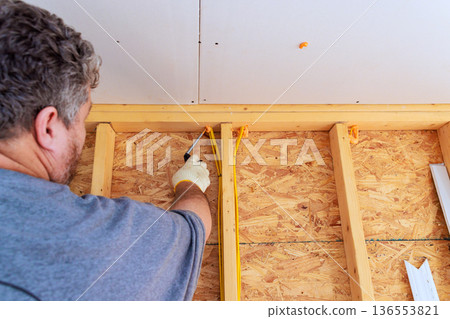 Workshop in house shows worker working on wooden wall framing at construction site Workshop in house shows worker working on wooden wall framing at construction site 136553821