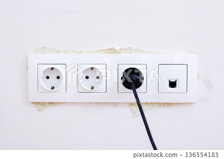 Outdated wall socket featuring black plug and network port on stained plaster surface Outdated wall socket featuring black plug and network port on stained plaster surface 136554183