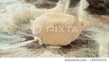 Dough Ball Dropping into Flour. Flour Explosion Effect During Baking Preparation on Wooden TableDough Ball Dropping into Flour. Flour Explosion Effect During Baking Preparation on Wooden Table 136554310