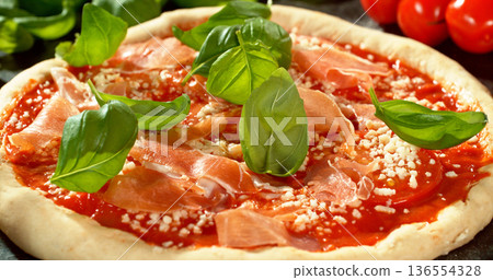 Shot of fresh basil leaves falling onto raw pizza dough topped with tomato sauce and mozzarella. Cinematic detail of Italian pizza preparation on a floured wooden table. Shot of fresh basil leaves falling onto raw pizza dough topped with tomato sauce and mozzarella. Cinematic detail of Italian pizza preparation on a floured wooden table. 136554328