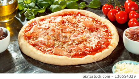 Prepared pizza dough with tomato sauce and mozzarella. Italian pizza preparation on rustic wooden table. Prepared pizza dough with tomato sauce and mozzarella. Italian pizza preparation on rustic wooden table. 136554329