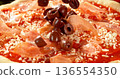 Closeup of black olives falling onto fresh pizza with tomato sauce, mozzarella and ham. Dynamic food motion highlights texture, freshness and Italian pizza preparation concept. 136554350