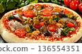 Closeup of black olives falling onto fresh pizza with tomato sauce, mozzarella and ham. Dynamic food motion highlights texture, freshness and Italian pizza preparation concept. 136554351