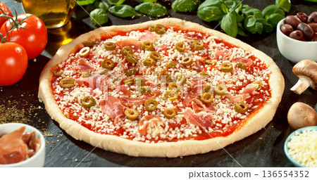 Prepared pizza dough with tomato sauce and mozzarella. Italian pizza preparation on rustic wooden table. Prepared pizza dough with tomato sauce and mozzarella. Italian pizza preparation on rustic wooden table. 136554352