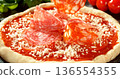 Closeup of salami slices falling onto prepared pizza base with tomato sauce and mozzarella. Raw dough surrounded by fresh ingredients. Concept of pizza preparation and baking. 136554355