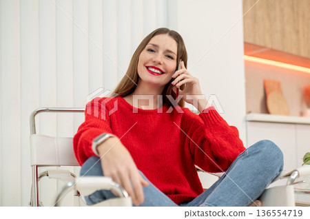 Pretty woman in red sweater talking on the phone 136554719