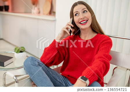 Pretty woman in red sweater talking on the phone 136554721
