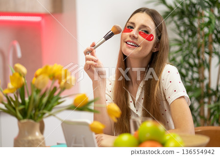 Long-haired beautiful young woman with a face brush sitting at the table 136554942