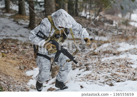 Soldier In White Winter Camouflage Climbing Snowy Slope With Rifle During Military Training 136555659