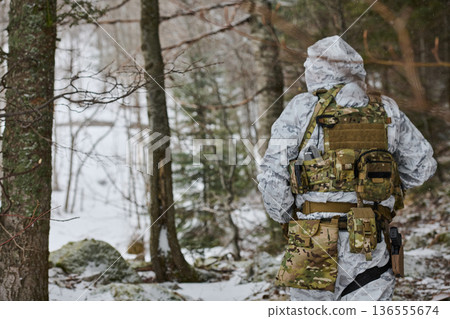 Soldier In Winter Camouflage Patrols Snowy Forest With Tactical Gear And Backpack Soldier In Winter Camouflage Patrols Snowy Forest With Tactical Gear And Backpack 136555674