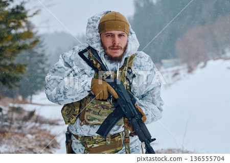 Soldier In White Winter Camouflage Holding Assault Rifle During Snowy Forest Patrol 136555704