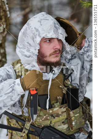 Bearded Soldier In Winter White Camouflage With Tactical Gear Knife And Rifle In Snowy Forest 136555711