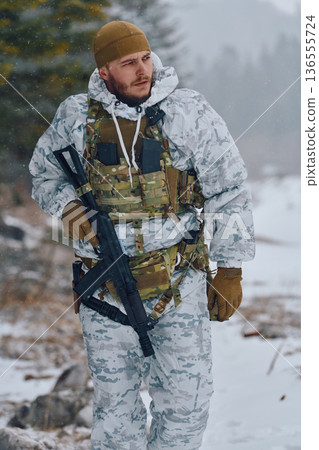 Winter Soldier in White Camouflage With Tactical Gear and Rifle Patrols Snowy Forest 136555724