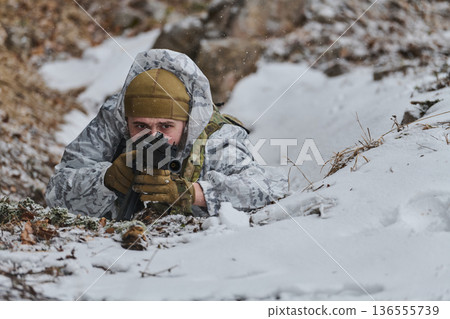 Soldier in Winter Camouflage Prone With Rifle Aiming Through Snow in Forest Trench Soldier in Winter Camouflage Prone With Rifle Aiming Through Snow in Forest Trench 136555739