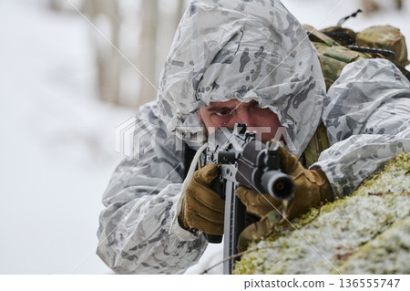 Soldier In White Winter Camouflage Aiming Rifle While Lying Prone In Snowy Forest 136555747