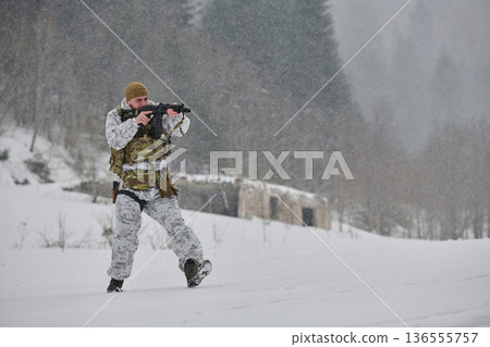 Soldier in Winter Camouflage Aiming Rifle During Snowy Military Training Patrol in Forest 136555757