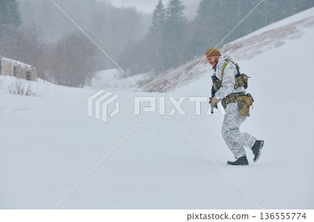 Soldier In White Camouflage Walking Through Snowy Winter Landscape With Tactical Gear And Rifle Soldier In White Camouflage Walking Through Snowy Winter Landscape With Tactical Gear And Rifle 136555774