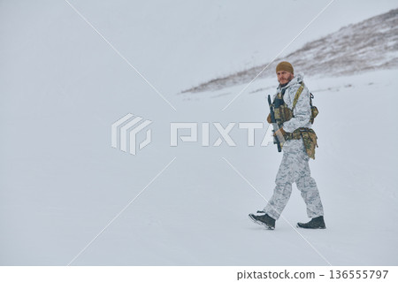 Soldier in White Winter Camouflage Walking Through Snowy Mountain Landscape With Rifle And Gear Soldier in White Winter Camouflage Walking Through Snowy Mountain Landscape With Rifle And Gear 136555797