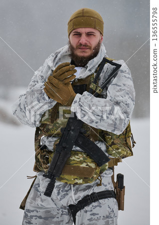 Armed Soldier In Winter Camouflage Gear Holding Rifle In Snowy Environment With Tactical Vest 136555798