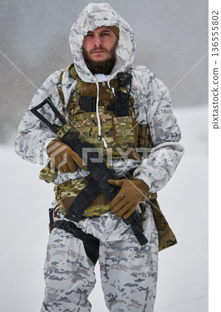 Winter Soldier in White Snow Camouflage Tactical Gear Holding Rifle During Cold Weather Patrol 136555802