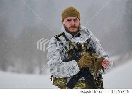 Armed Soldier in White Winter Camouflage Holding Gloves During Snowy Forest Patrol 136555806